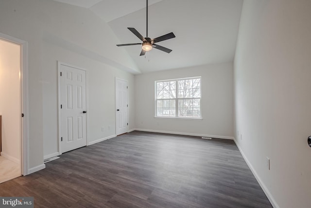 unfurnished bedroom with ceiling fan, vaulted ceiling, dark hardwood / wood-style flooring, and multiple closets