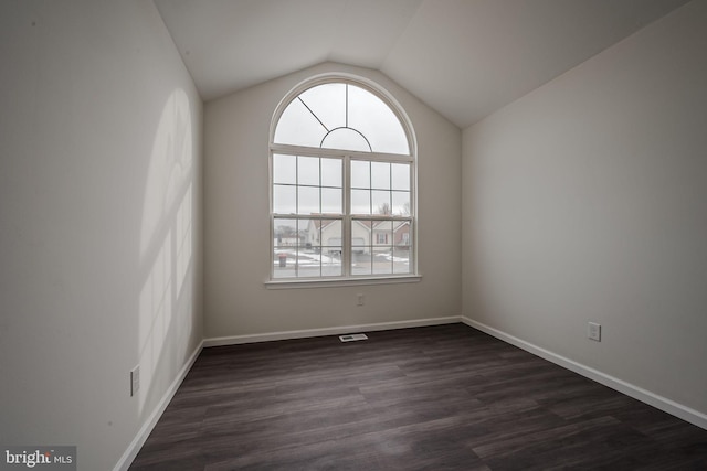 empty room with dark hardwood / wood-style flooring and lofted ceiling