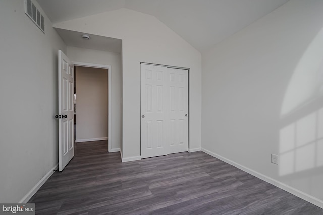 unfurnished bedroom featuring dark hardwood / wood-style floors, a closet, and vaulted ceiling