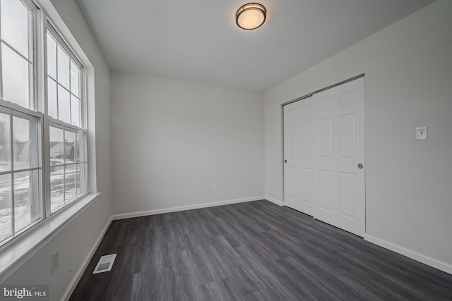 empty room featuring dark wood-type flooring and a wealth of natural light