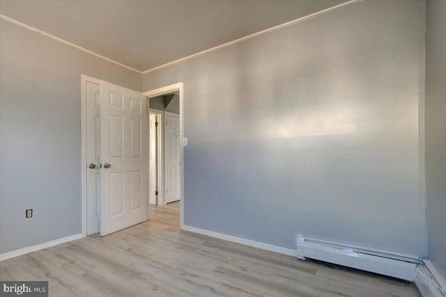 unfurnished room with ornamental molding, light hardwood / wood-style floors, and a baseboard heating unit