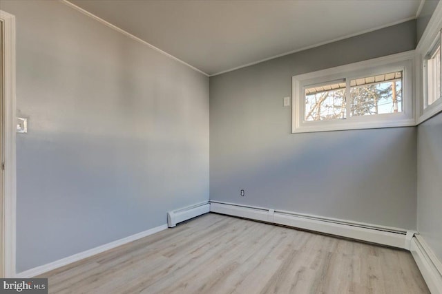 spare room featuring a baseboard heating unit, crown molding, and light hardwood / wood-style floors