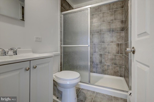 bathroom with vanity, toilet, a shower with shower door, and tile patterned flooring