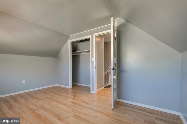 unfurnished bedroom with vaulted ceiling, light hardwood / wood-style floors, and a closet