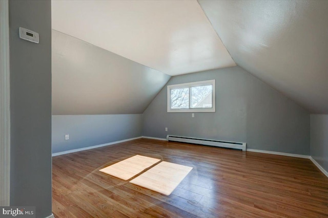 bonus room with a baseboard heating unit, wood-type flooring, and vaulted ceiling