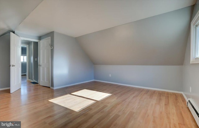 additional living space with lofted ceiling, a baseboard radiator, and light hardwood / wood-style floors