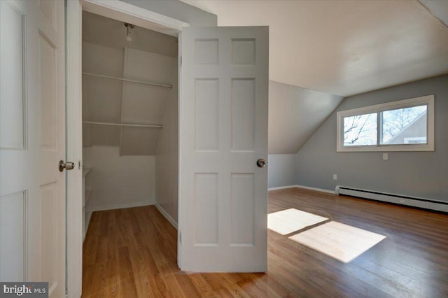 bonus room featuring light hardwood / wood-style floors, vaulted ceiling, and a baseboard heating unit