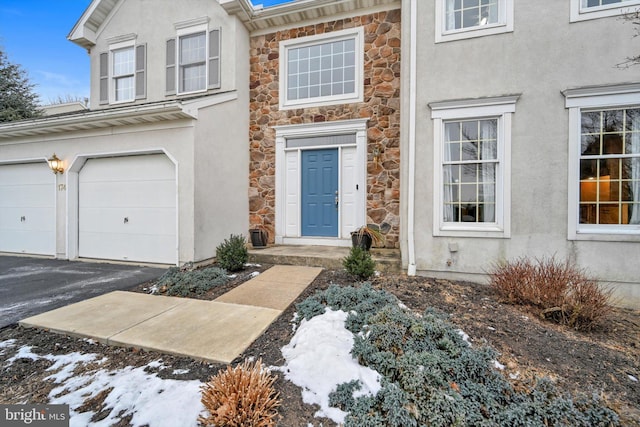 snow covered property entrance featuring a garage