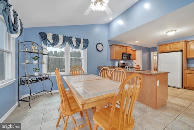 dining space featuring ceiling fan, light tile patterned flooring, sink, and lofted ceiling