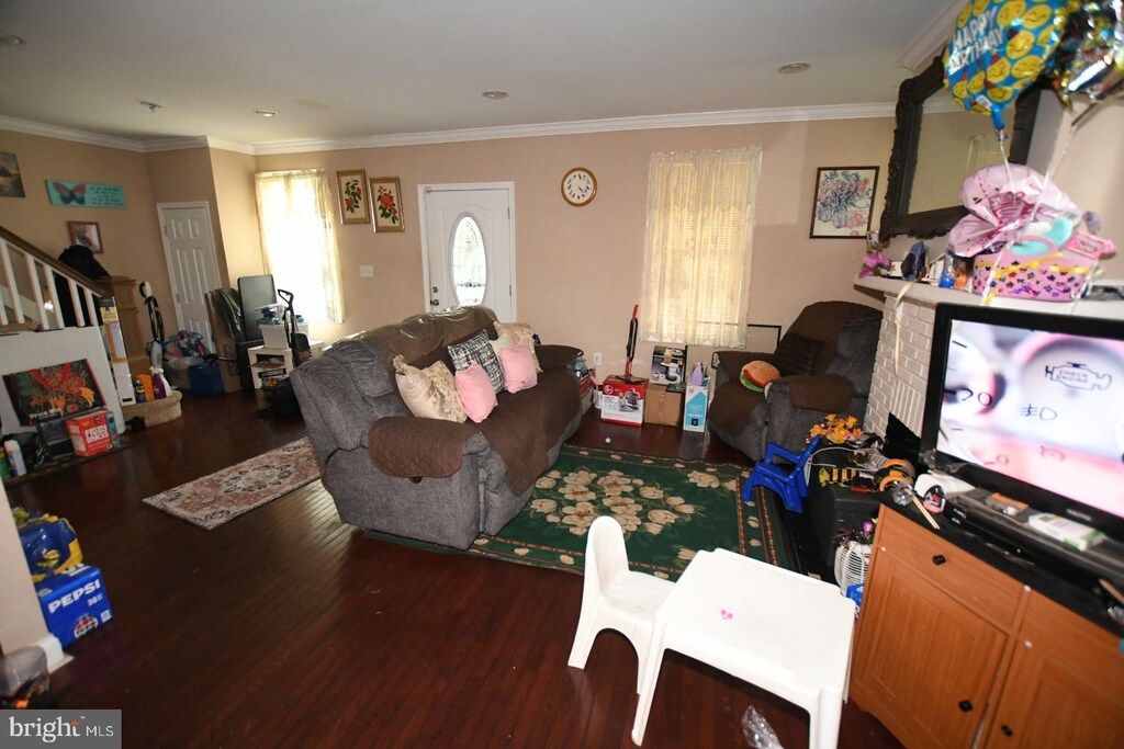 5211 Bosworth Ave, Baltimore, MD 21207 - living area featuring wood finished floors, ornamental molding, and stairs