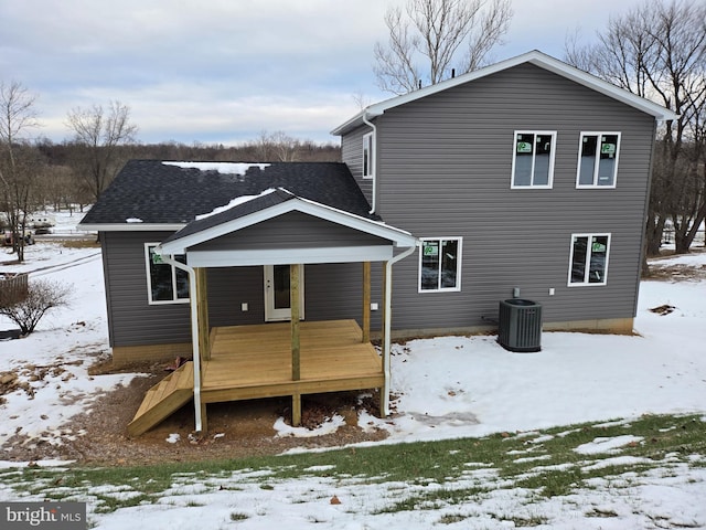 snow covered rear of property featuring central AC