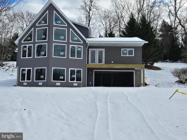 snow covered house featuring a garage