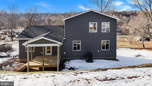 snow covered house featuring central AC unit