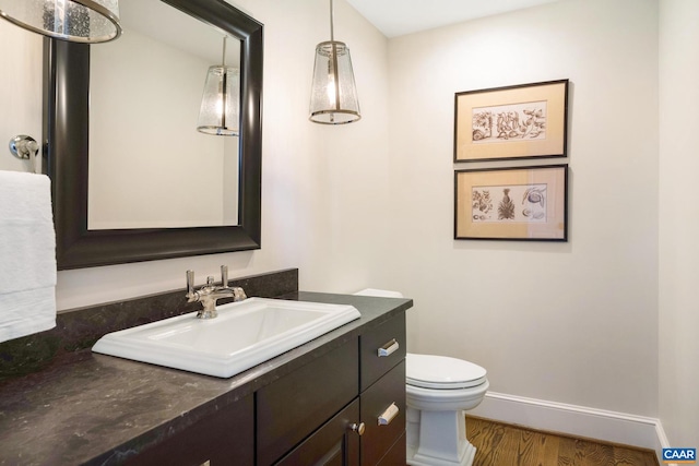 bathroom with hardwood / wood-style flooring, toilet, and vanity