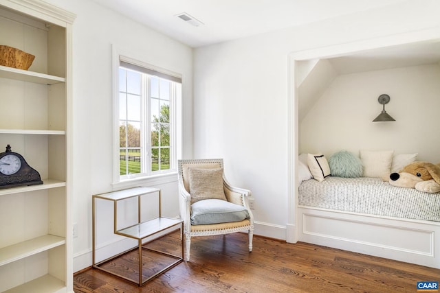 sitting room featuring built in shelves, dark wood-type flooring, and a wealth of natural light