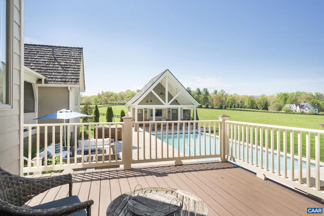 wooden terrace featuring a fenced in pool, an outbuilding, and a yard