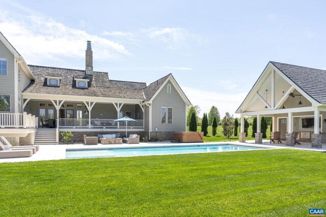 rear view of property featuring a patio area, a lawn, and a hot tub