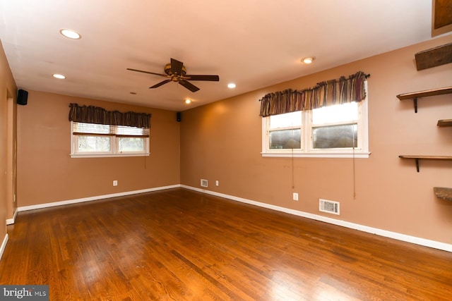 empty room featuring ceiling fan, a healthy amount of sunlight, and dark hardwood / wood-style floors