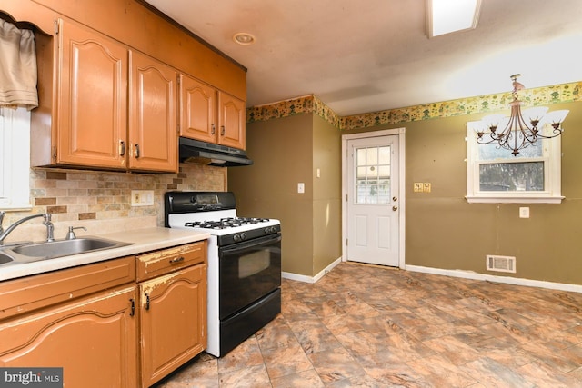 kitchen with range with gas cooktop, decorative light fixtures, decorative backsplash, sink, and a chandelier