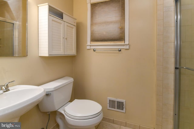 bathroom featuring a shower with shower door, tile patterned floors, sink, and toilet