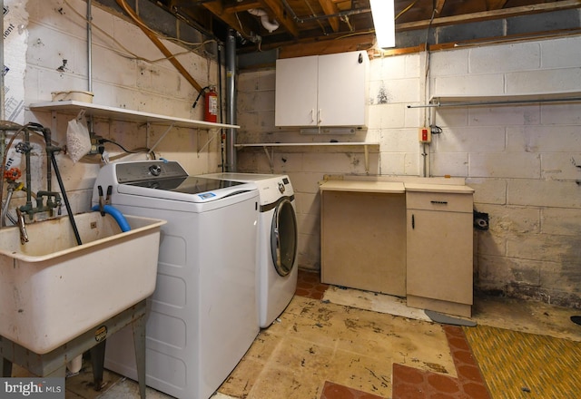 laundry area featuring cabinets, washer and clothes dryer, and sink