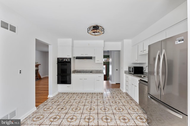 kitchen with light tile patterned floors, black appliances, white cabinets, and light stone counters