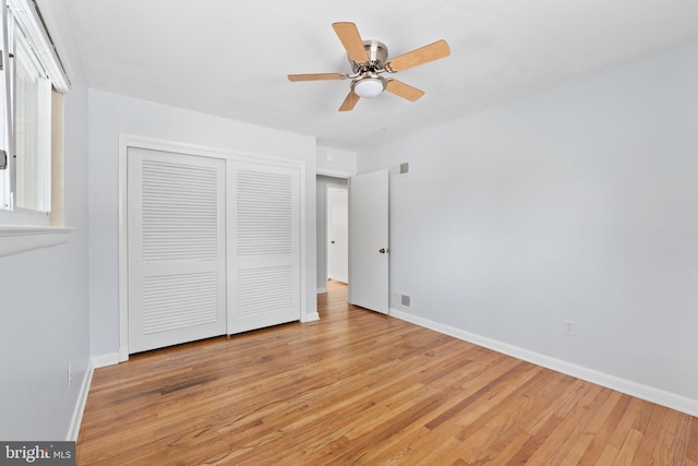 unfurnished bedroom featuring ceiling fan, a closet, and light wood-type flooring