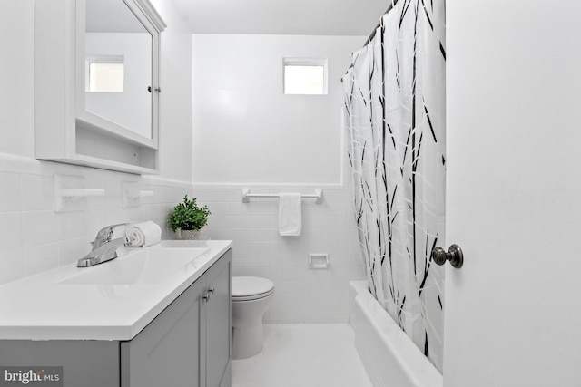 full bathroom featuring vanity, toilet, tile walls, and shower / tub combo