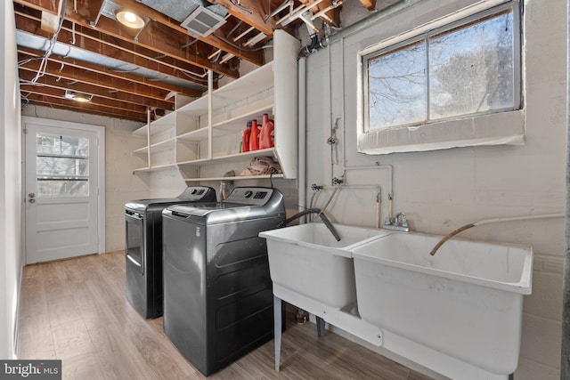 laundry area featuring separate washer and dryer, hardwood / wood-style floors, and sink