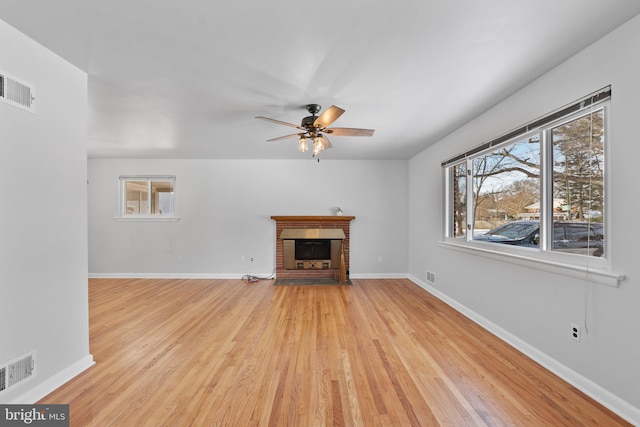 unfurnished living room featuring light hardwood / wood-style floors, ceiling fan, and a fireplace