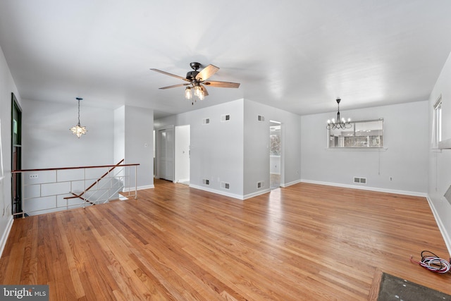 unfurnished living room with ceiling fan with notable chandelier and light hardwood / wood-style flooring