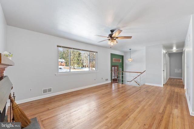 unfurnished living room featuring ceiling fan, light wood-type flooring, and a brick fireplace