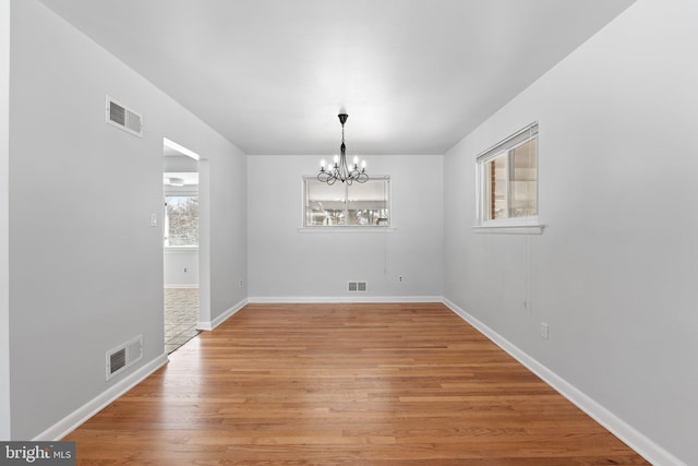 unfurnished dining area featuring light hardwood / wood-style flooring and a chandelier