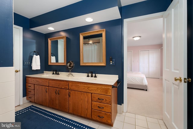 full bath with a sink, baseboards, double vanity, and tile patterned flooring