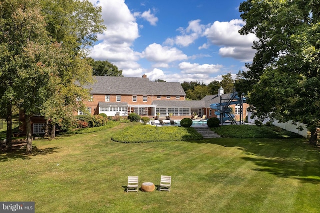 back of house featuring an outdoor pool, a yard, and fence