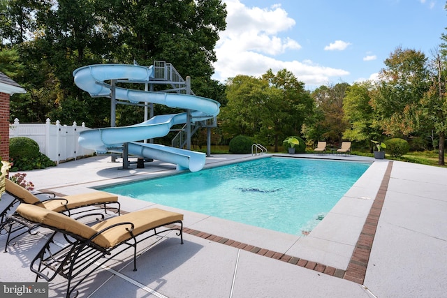 outdoor pool with fence, a water slide, and a patio area