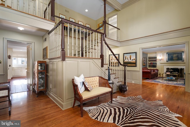 stairs featuring a high ceiling, wood finished floors, a fireplace, and a decorative wall