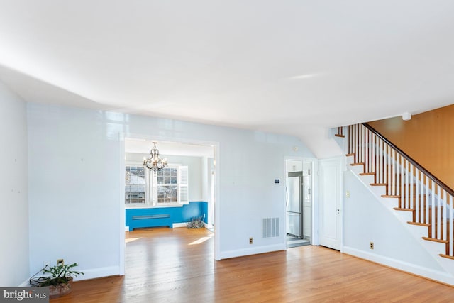 unfurnished living room with an inviting chandelier and light hardwood / wood-style flooring