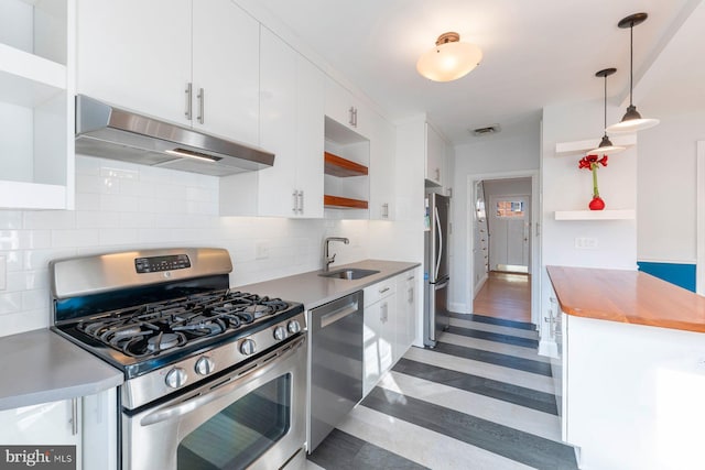 kitchen with sink, hanging light fixtures, stainless steel appliances, tasteful backsplash, and white cabinets