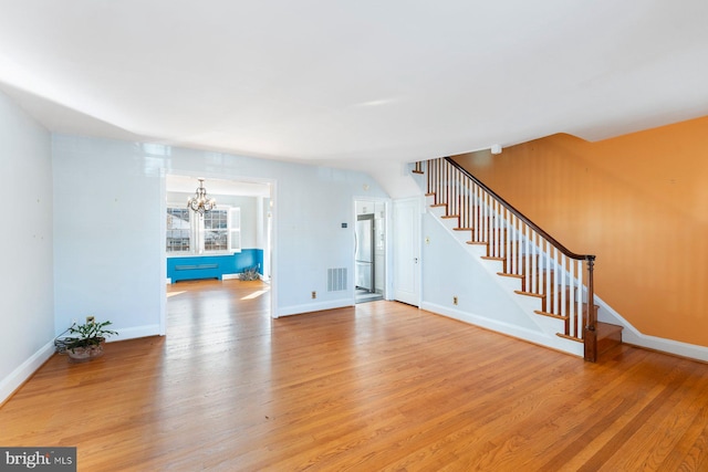 unfurnished living room featuring light hardwood / wood-style floors and a chandelier