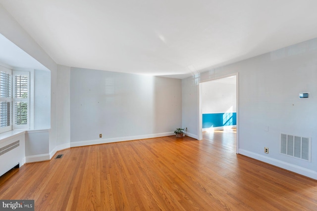 spare room featuring radiator heating unit and light wood-type flooring