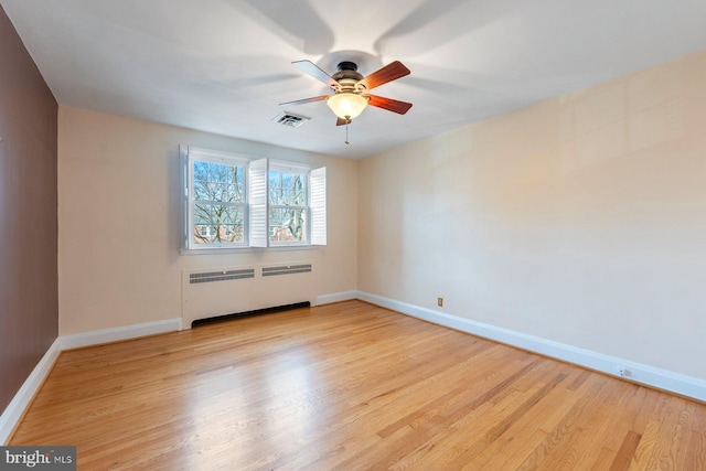 empty room with ceiling fan, radiator heating unit, and light wood-type flooring