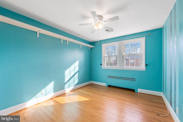 empty room with ceiling fan, radiator heating unit, and light hardwood / wood-style floors