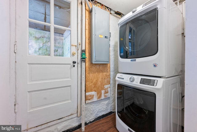 laundry room with stacked washer / drying machine, electric panel, and dark hardwood / wood-style flooring