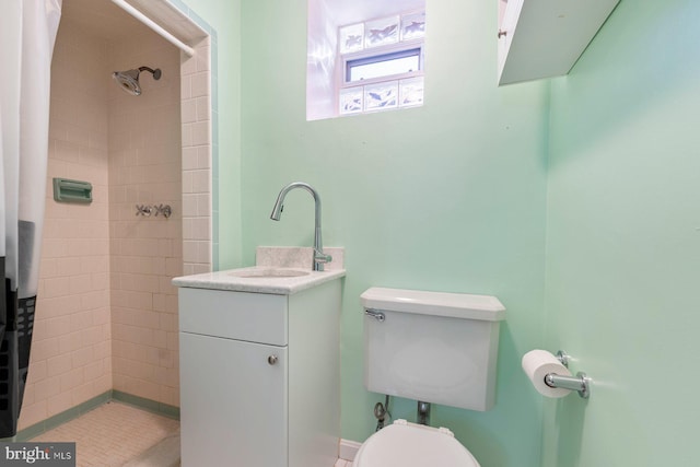 bathroom featuring vanity, a tile shower, and toilet