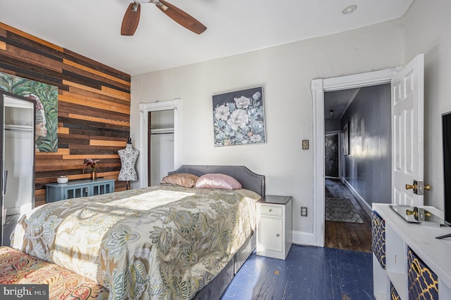 bedroom with ceiling fan, a closet, dark hardwood / wood-style floors, and wood walls