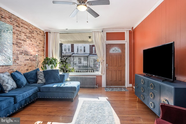 living room featuring ceiling fan, wood walls, crown molding, light hardwood / wood-style flooring, and radiator