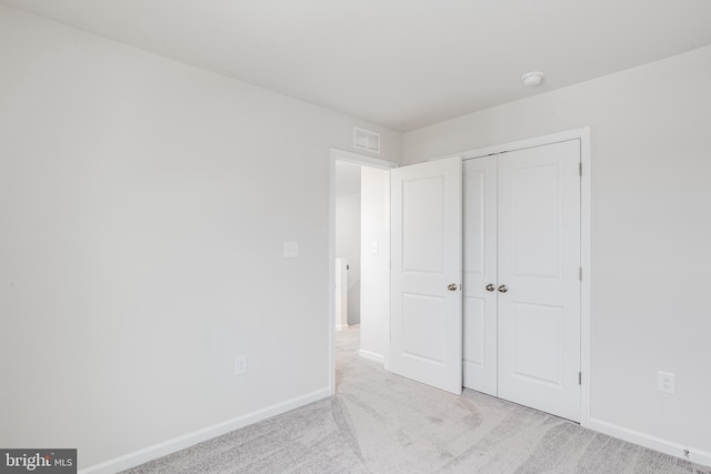 unfurnished bedroom with a closet and light colored carpet