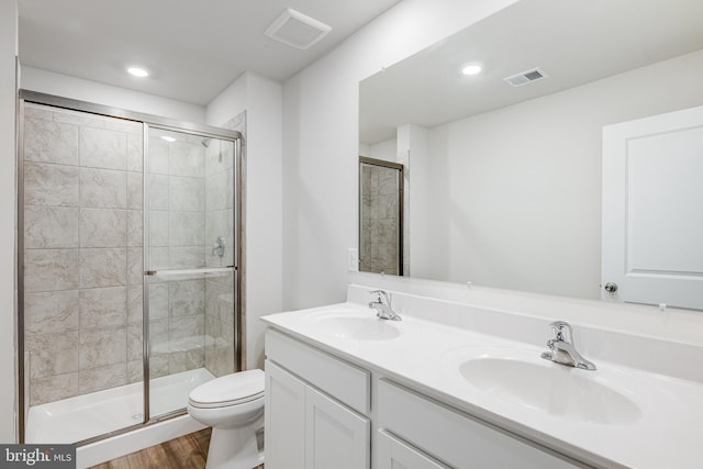 bathroom with toilet, wood-type flooring, a shower with door, and vanity