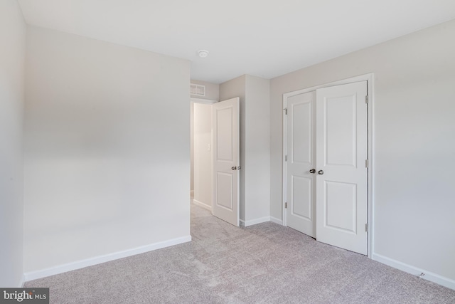 unfurnished bedroom featuring light colored carpet and a closet